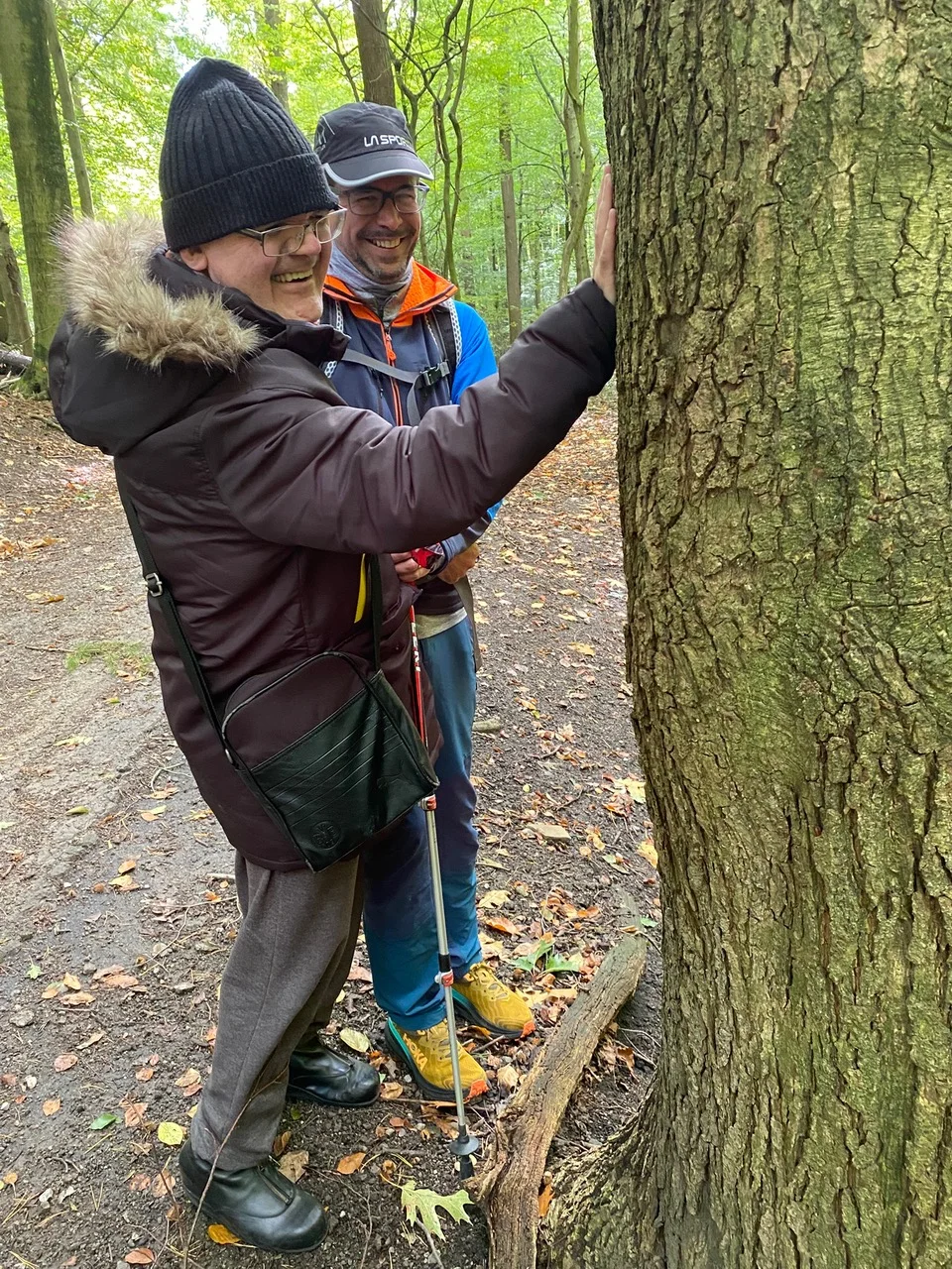 Eine blinde Frau ertastet mit Begleitung die Rinde eines Baumes im Wald. | © DAV Dortmund