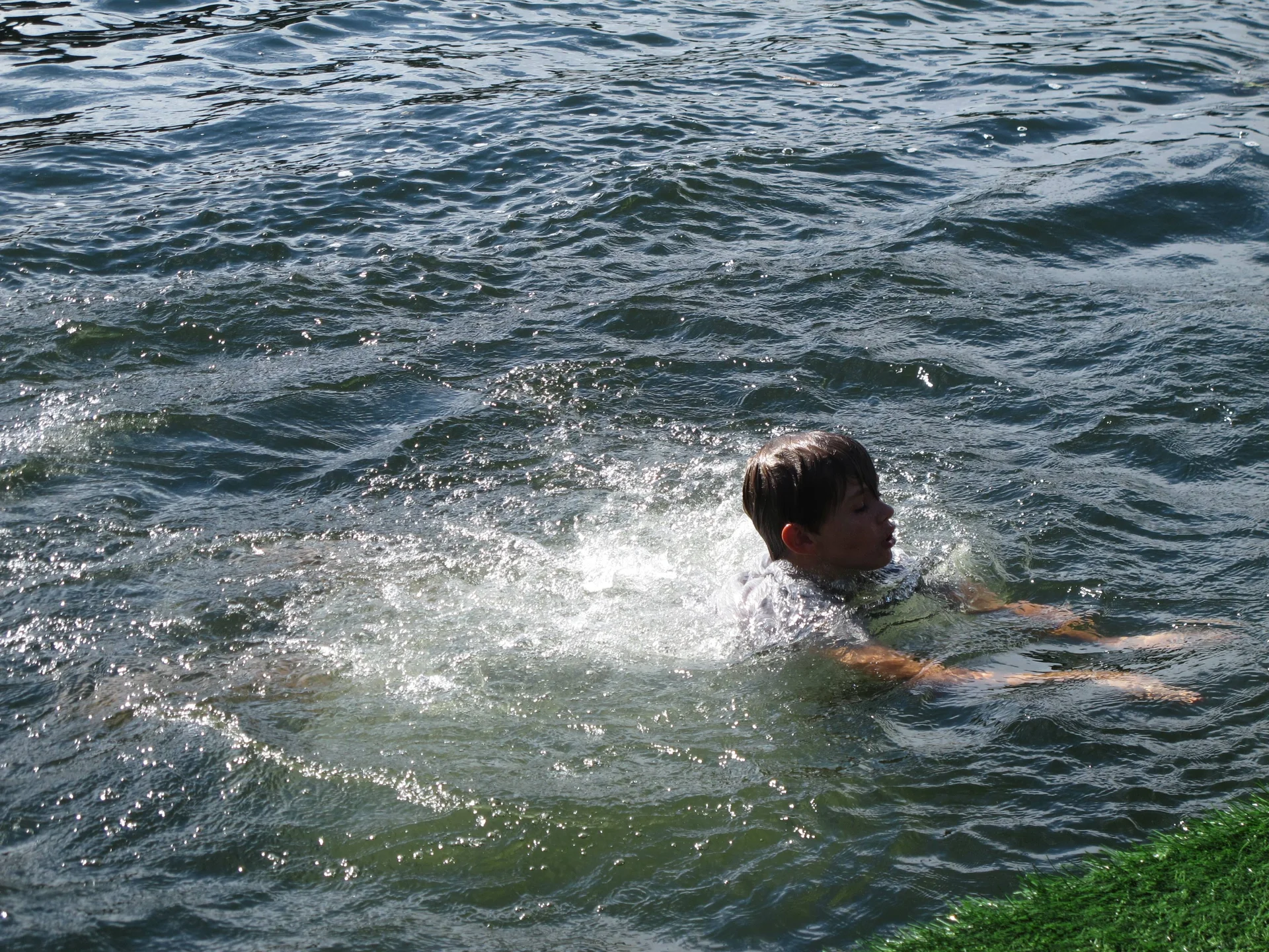 Ein Kind schwimmt Richtung Ufer, Wasser spritzt um ihn herum. | © DAV Dortmund