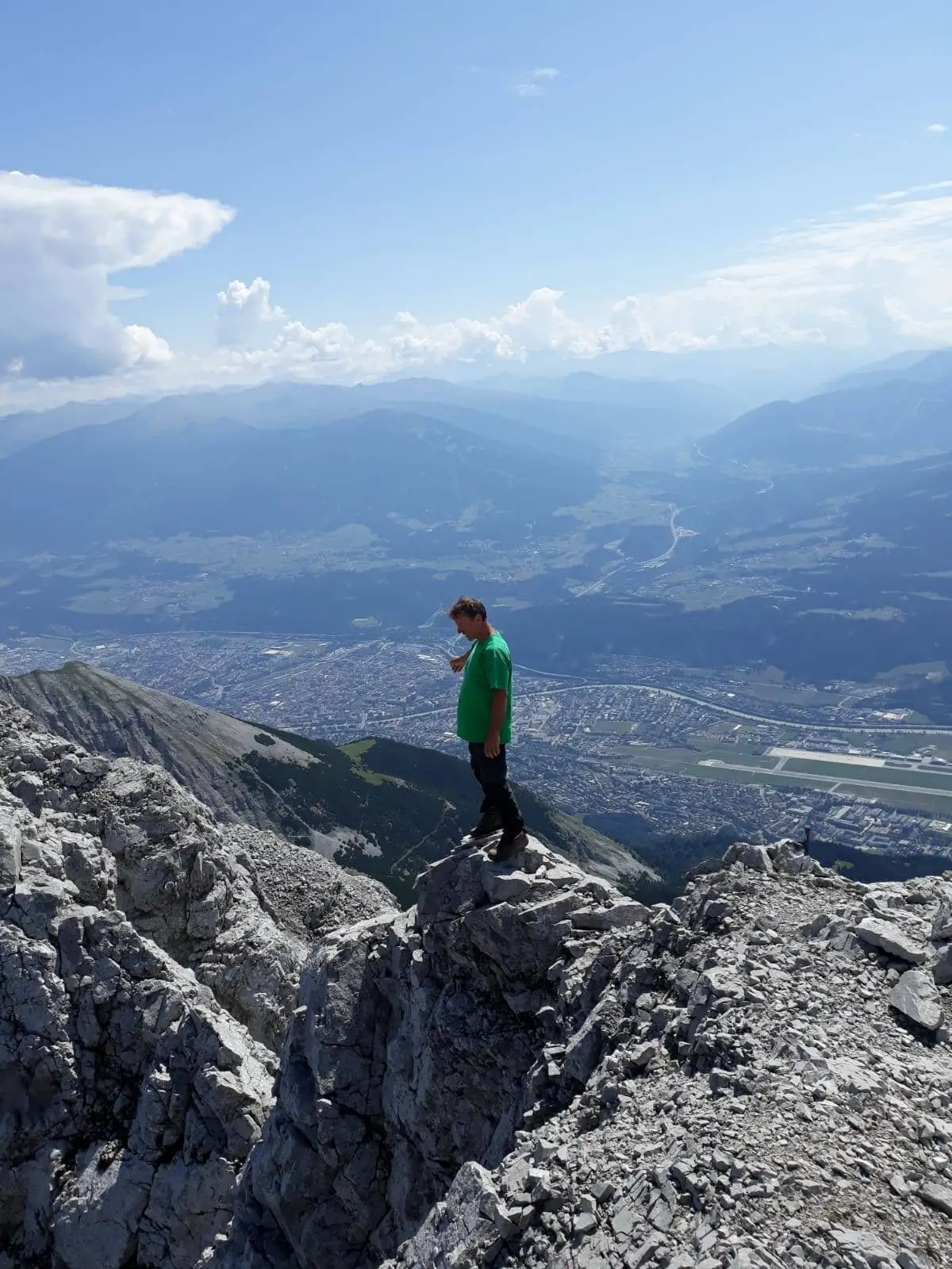 Ein Jugendlicher steht auf einem Felsvorsprung mit Blick auf das Tal und umliegende Berge. | © DAV Dortmund