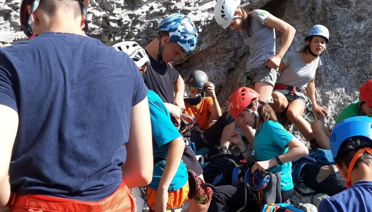 Jugendliche mit Kletterausrüstung bereiten sich in einer Gruppe unter einer Felswand auf eine Klettertour vor. | © DAV Dortmund