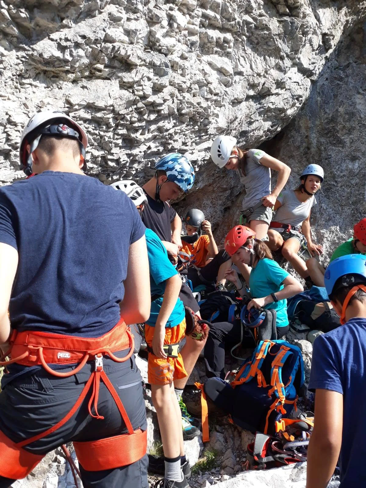 Jugendliche mit Kletterausrüstung bereiten sich in einer Gruppe unter einer Felswand auf eine Klettertour vor. | © DAV Dortmund