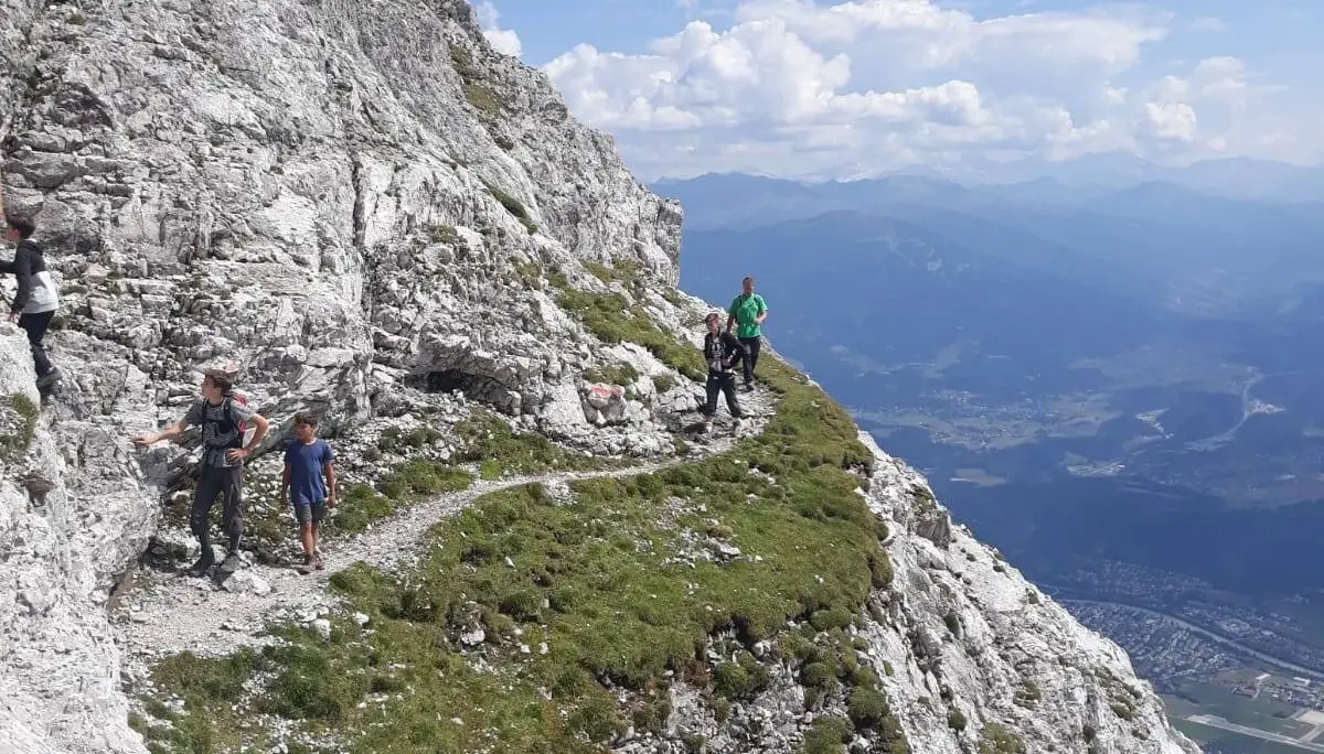 Wandergruppe auf einem schmalen felsigen Pfad mit Blick ins Tal und auf umliegende Berge. | © DAV Dortmund