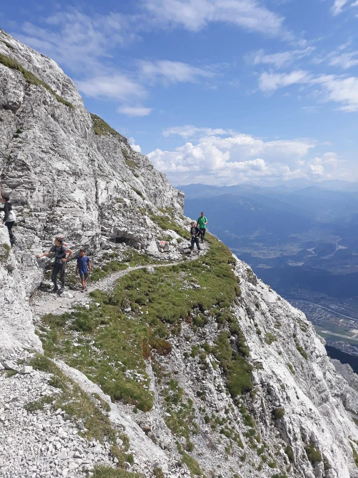 Wandergruppe auf einem schmalen felsigen Pfad mit Blick ins Tal und auf umliegende Berge. | © DAV Dortmund