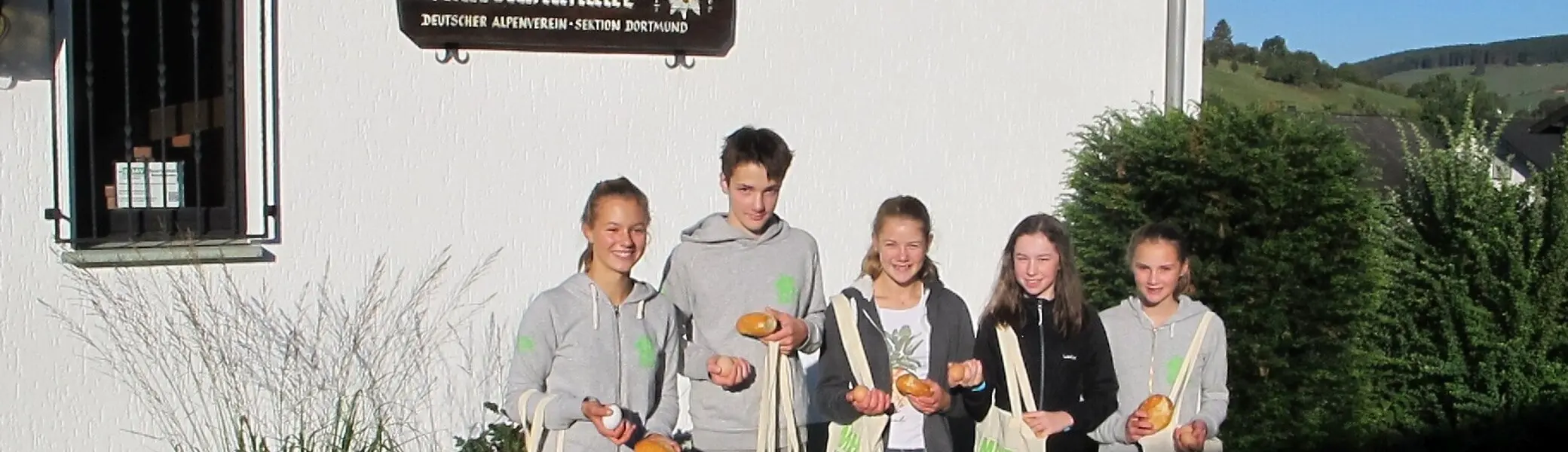 Fünf Jugendliche stehen vor einem Gebäude mit Brötchen und Mehrwegtaschen in der Hand. | © DAV Dortmund