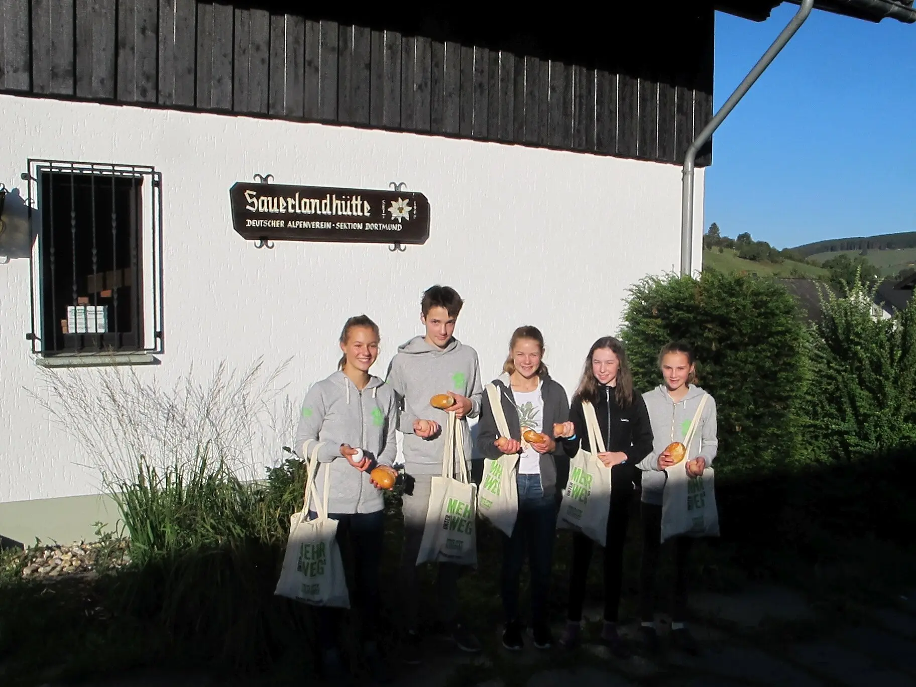 Fünf Jugendliche stehen vor einem Gebäude mit Brötchen und Mehrwegtaschen in der Hand. | © DAV Dortmund