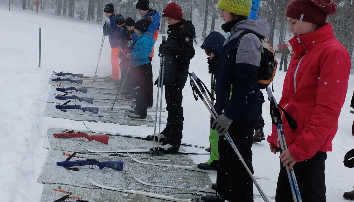 Kinder stehen auf einem Biathlon-Schießstand im Schnee mit Gewehren auf dem Boden. | © DAV Dortmund