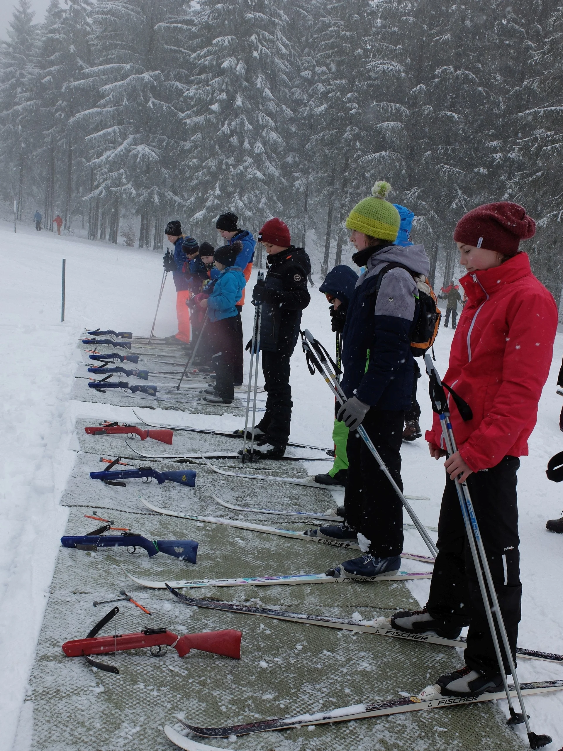 Kinder stehen auf einem Biathlon-Schießstand im Schnee mit Gewehren auf dem Boden. | © DAV Dortmund