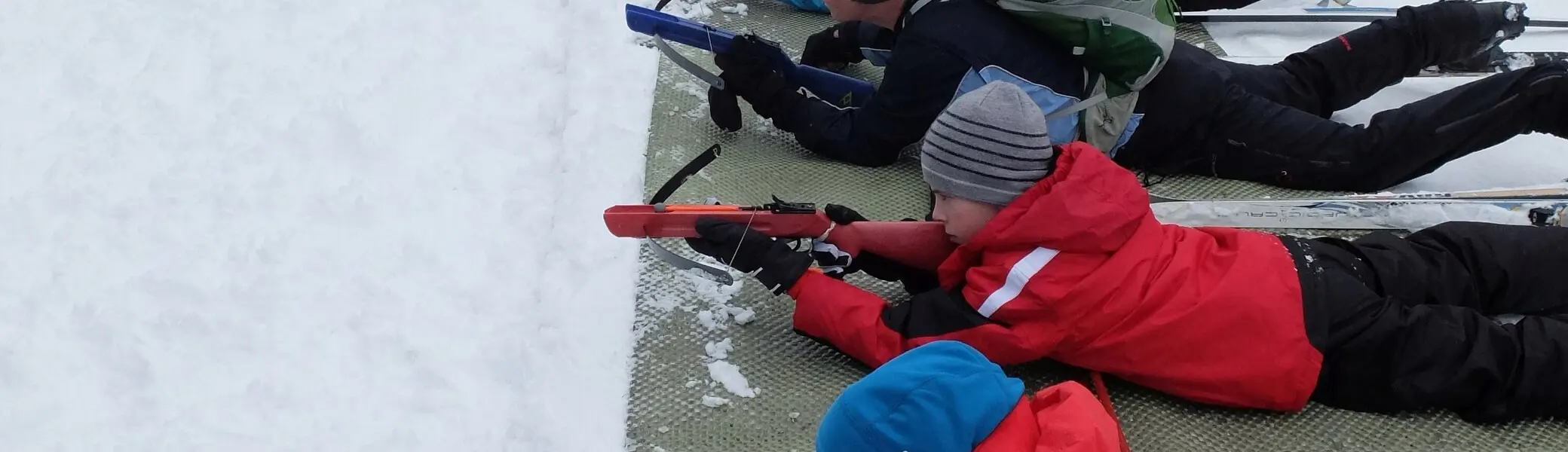Kinder liegen auf Matten im Schnee und zielen mit Biathlon-Gewehren auf eine Zielscheibe. | © DAV Dortmund