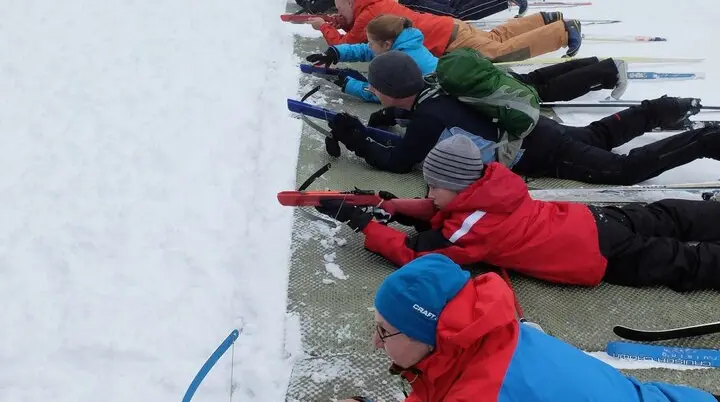 Kinder liegen auf Matten im Schnee und zielen mit Biathlon-Gewehren auf eine Zielscheibe. | © DAV Dortmund