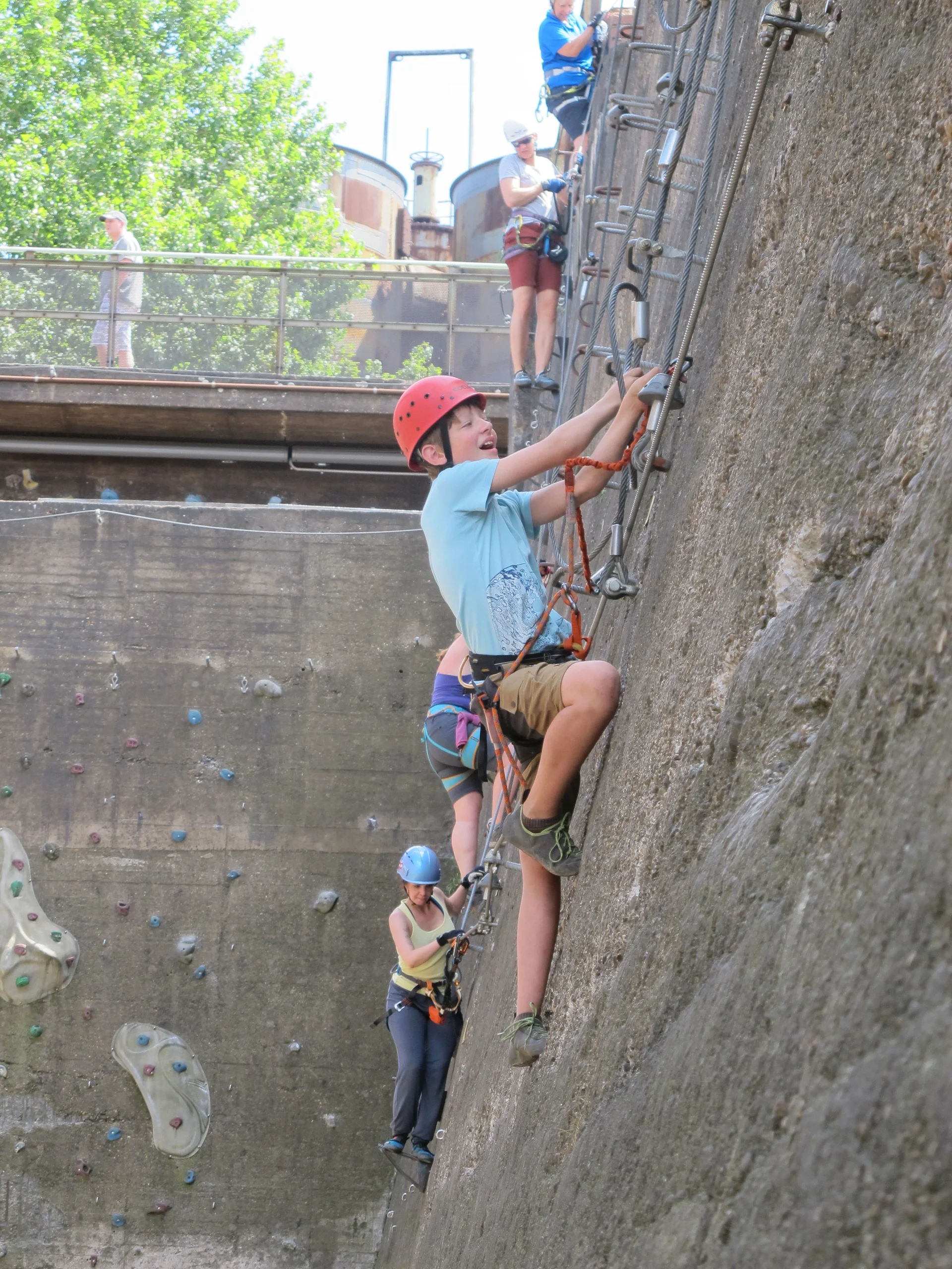 Jugendliche erklimmen eine Wand mit Eisenleitern im Klettersteig-Stil. | © DAV Dortmund