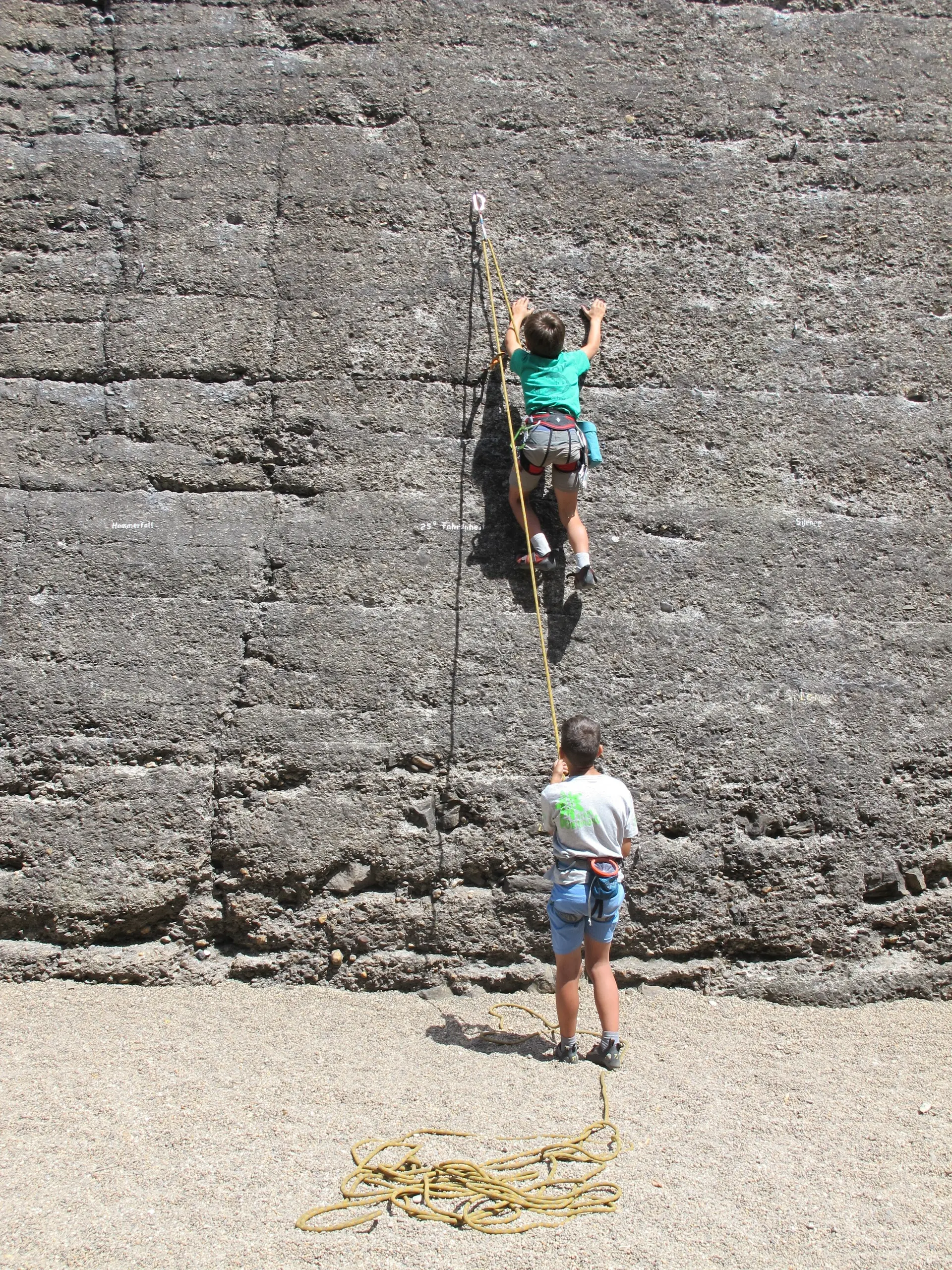 Ein Kind klettert an einer grauen Wand, eine Person sichert es von unten mit Seil. | © DAV Dortmund