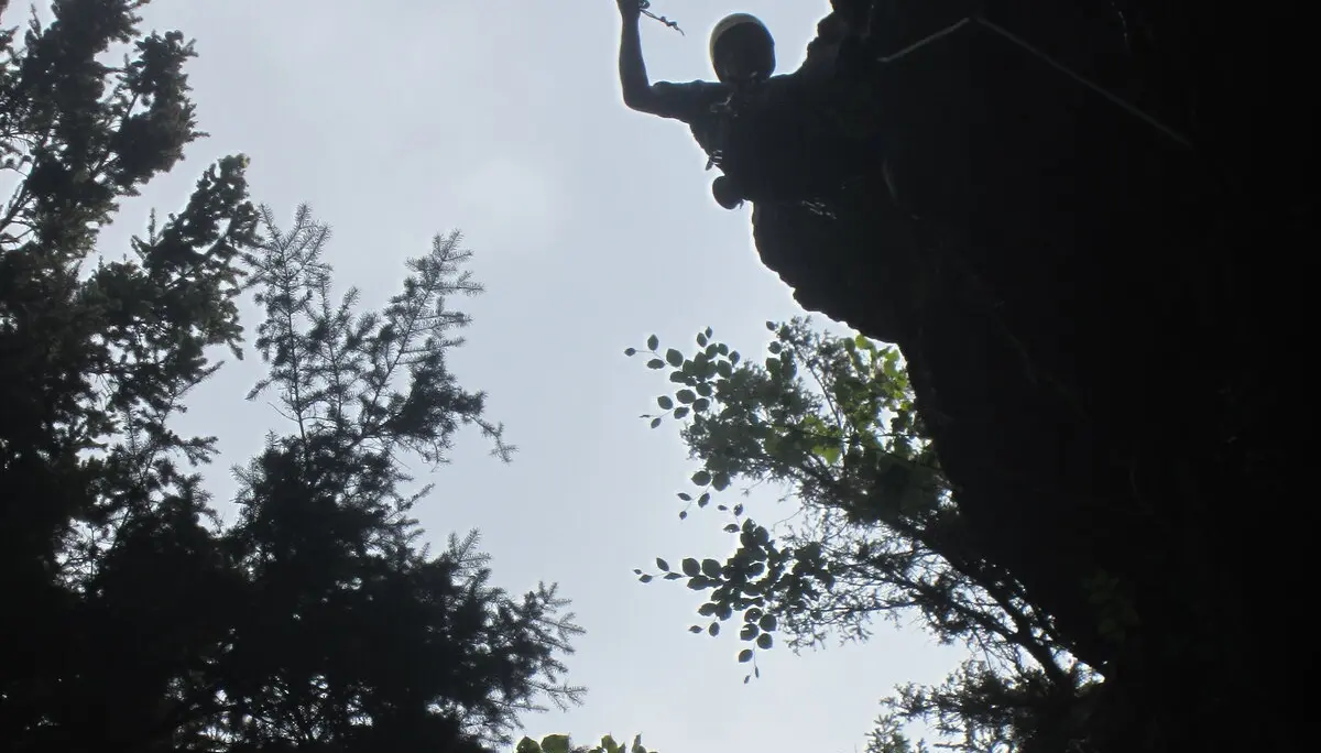 Silhouette eines Kletterers am Überhang mit erhobenem Arm. | © DAV Dortmund