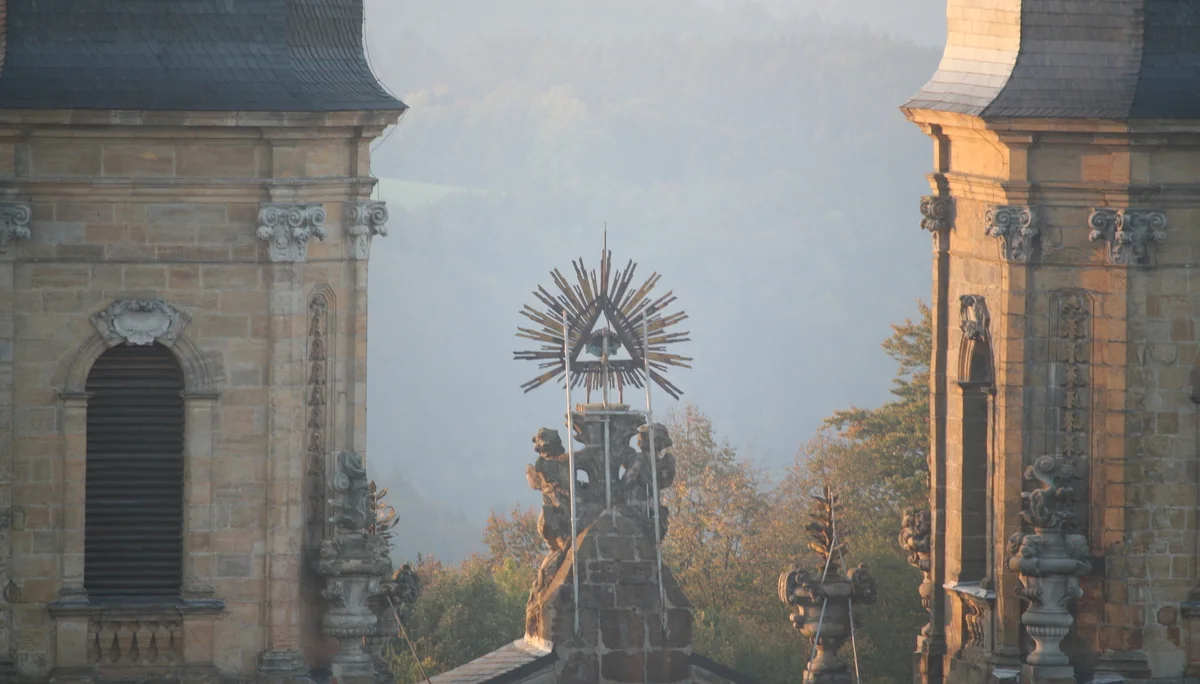 Blick auf zwei Türme eines Klosters mit einer leuchtenden Strahlensonne dazwischen im Morgenlicht. | © DAV Dortmund
