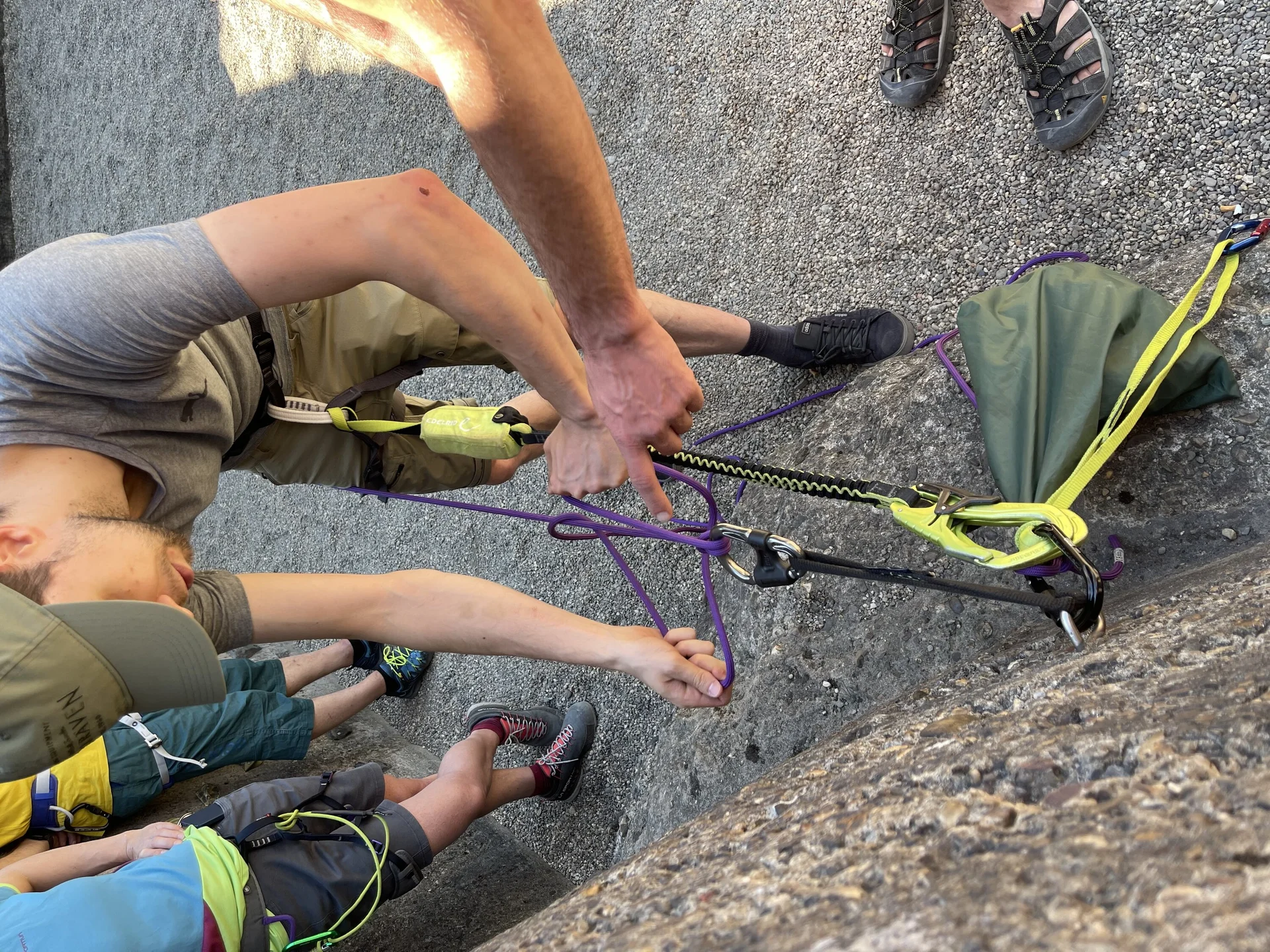 Ein junger Mann übt mit einem Partner den Aufbau eines Flaschenzugsystems am Fuß einer Wand. | © DAV Dortmund