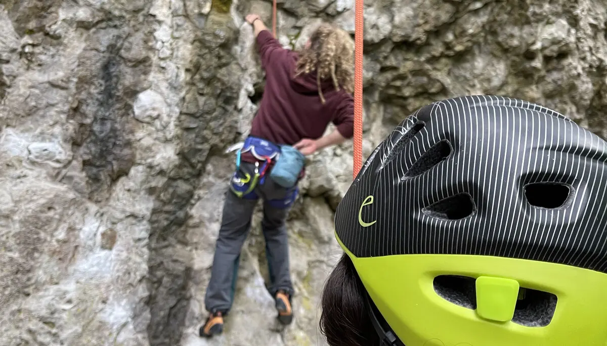 Eine Person mit Kletterhelm sichert eine andere, die eine steile Felswand hinaufklettert. | © DAV Dortmund