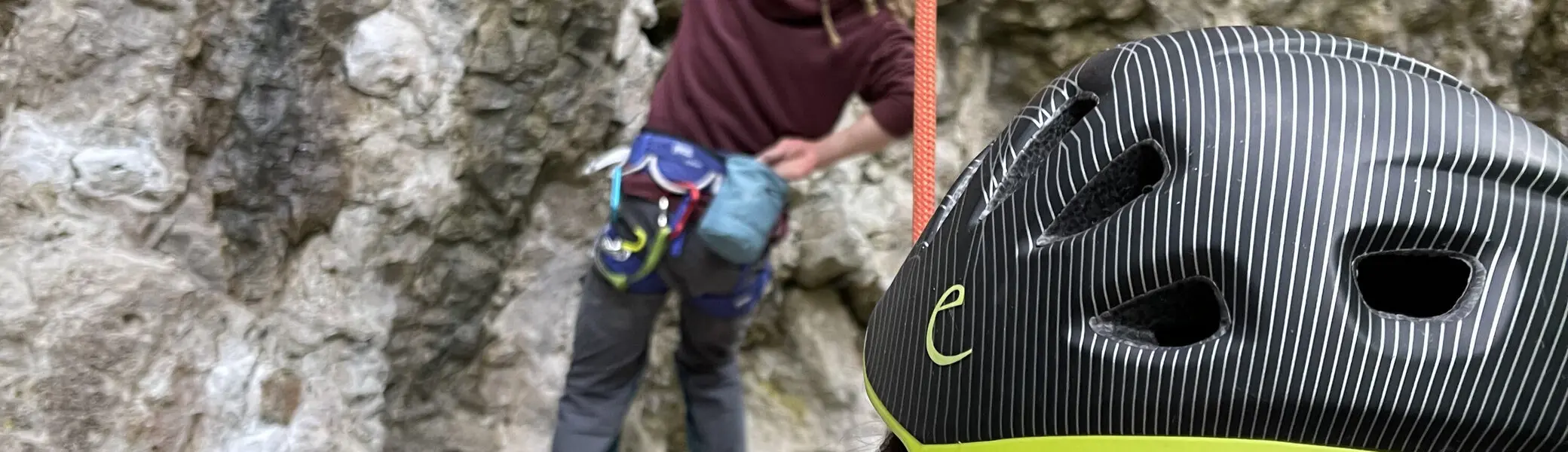 Eine Person mit Kletterhelm sichert eine andere, die eine steile Felswand hinaufklettert. | © DAV Dortmund