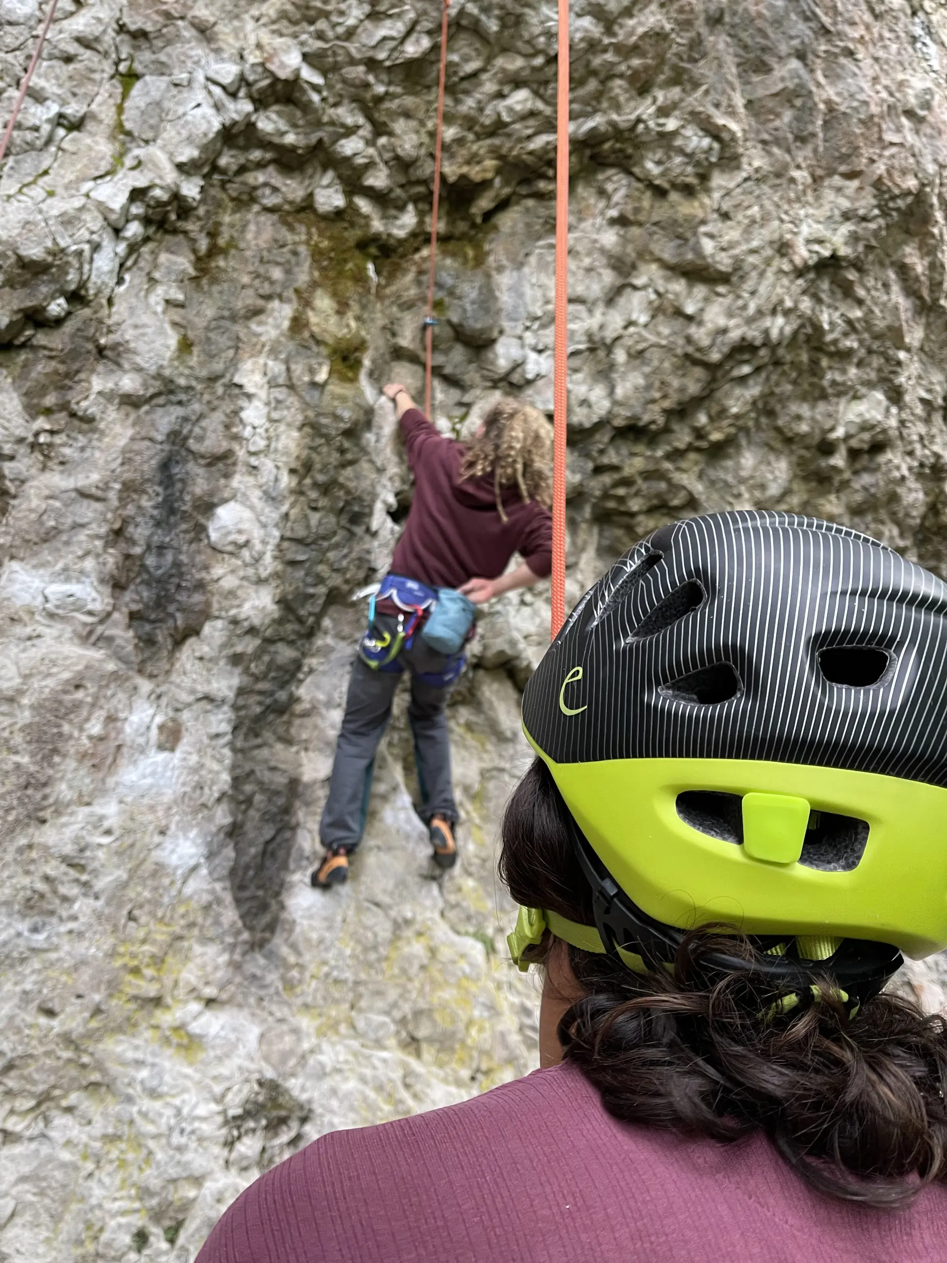 Eine Person mit Kletterhelm sichert eine andere, die eine steile Felswand hinaufklettert. | © DAV Dortmund