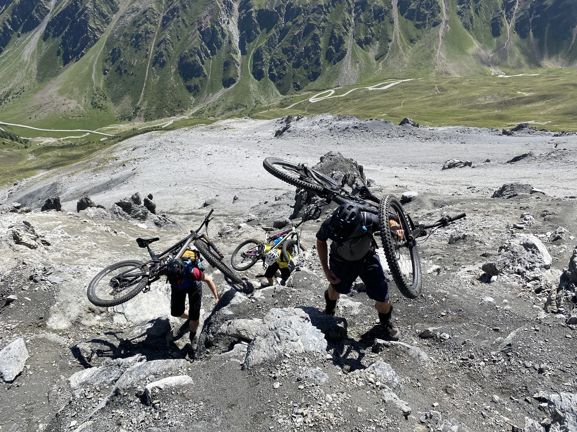 Drei Personen tragen ihre Mountainbikes über ein steiles, felsiges Gelände im Hochgebirge. | © DAV Dortmund