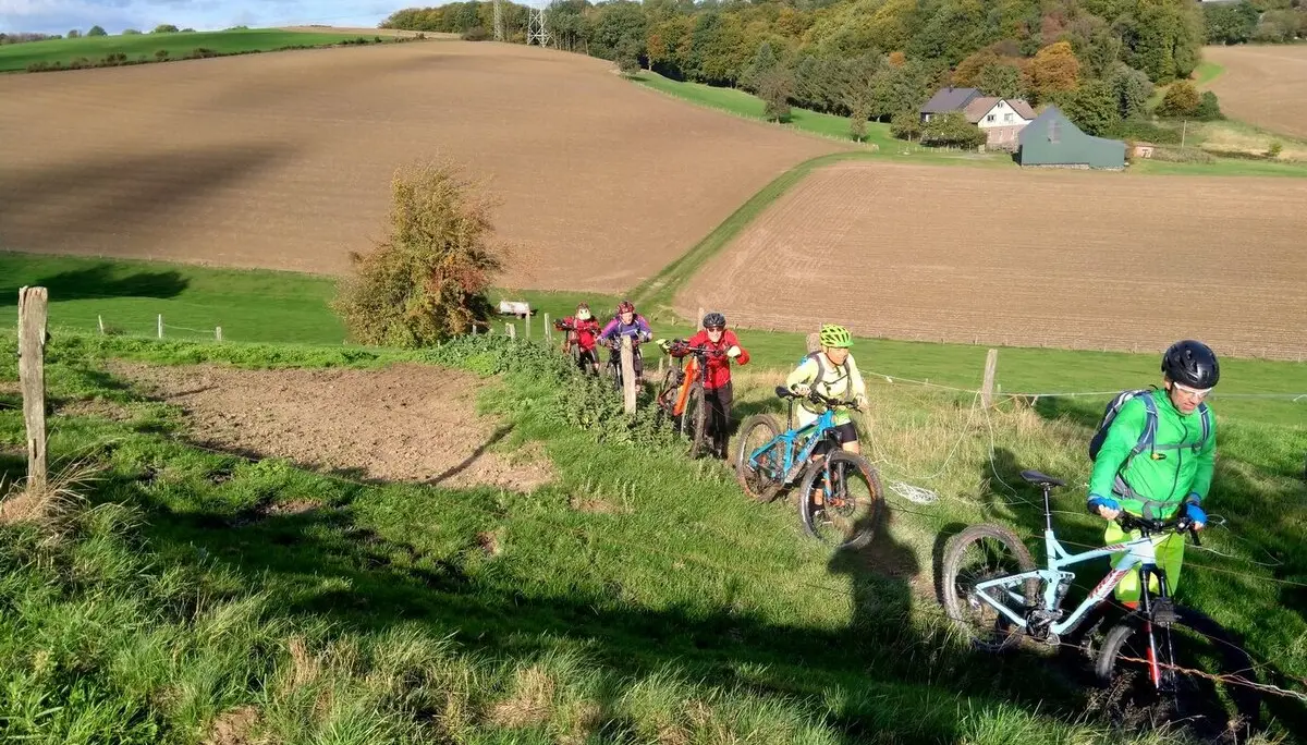 Gruppe von Mountainbiker*innen schiebt Räder einen steilen Pfad entlang. | © DAV Dortmund