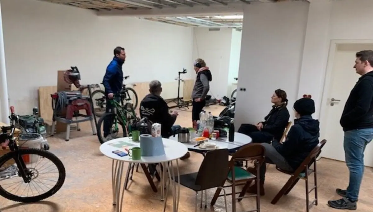 Mehrere Personen sitzen und stehen in einer Fahrradwerkstatt mit Werkzeugen und Rädern. | © DAV Dortmund