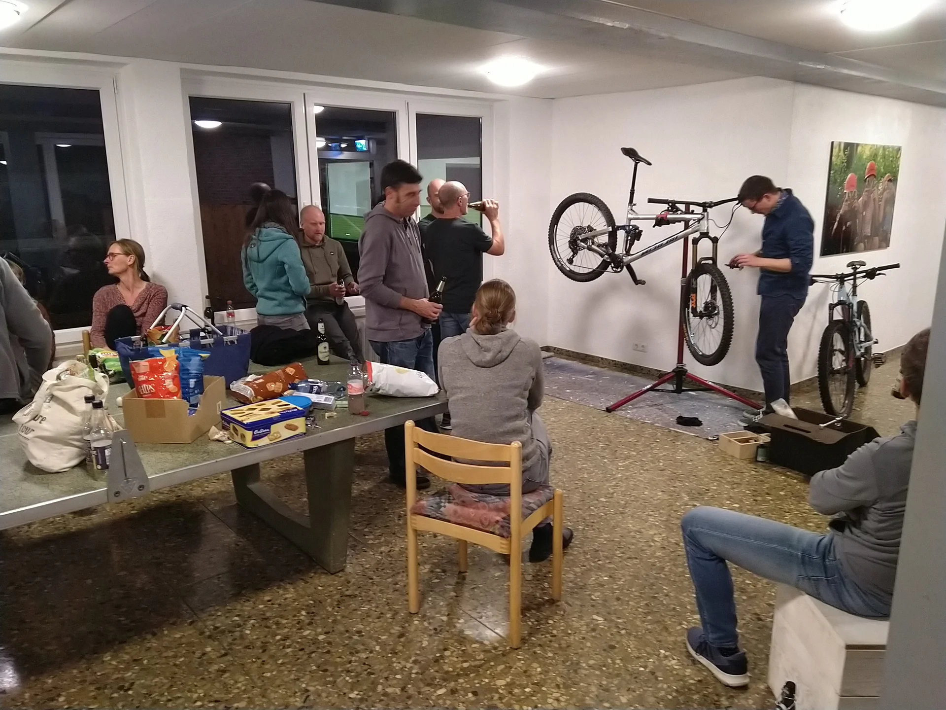 Mehrere Personen sitzen und stehen in einem Raum mit Werkzeugen, während zwei Mountainbikes gewartet werden. | © DAV Dortmund