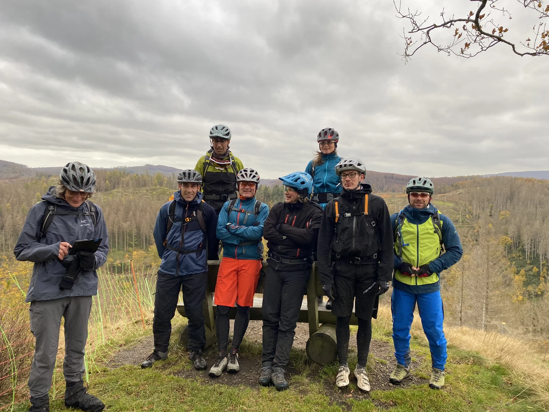 Acht Personen mit Helmen posieren an einem Aussichtspunkt mit weitem Blick über den herbstlichen Wald. | © DAV Dortmund