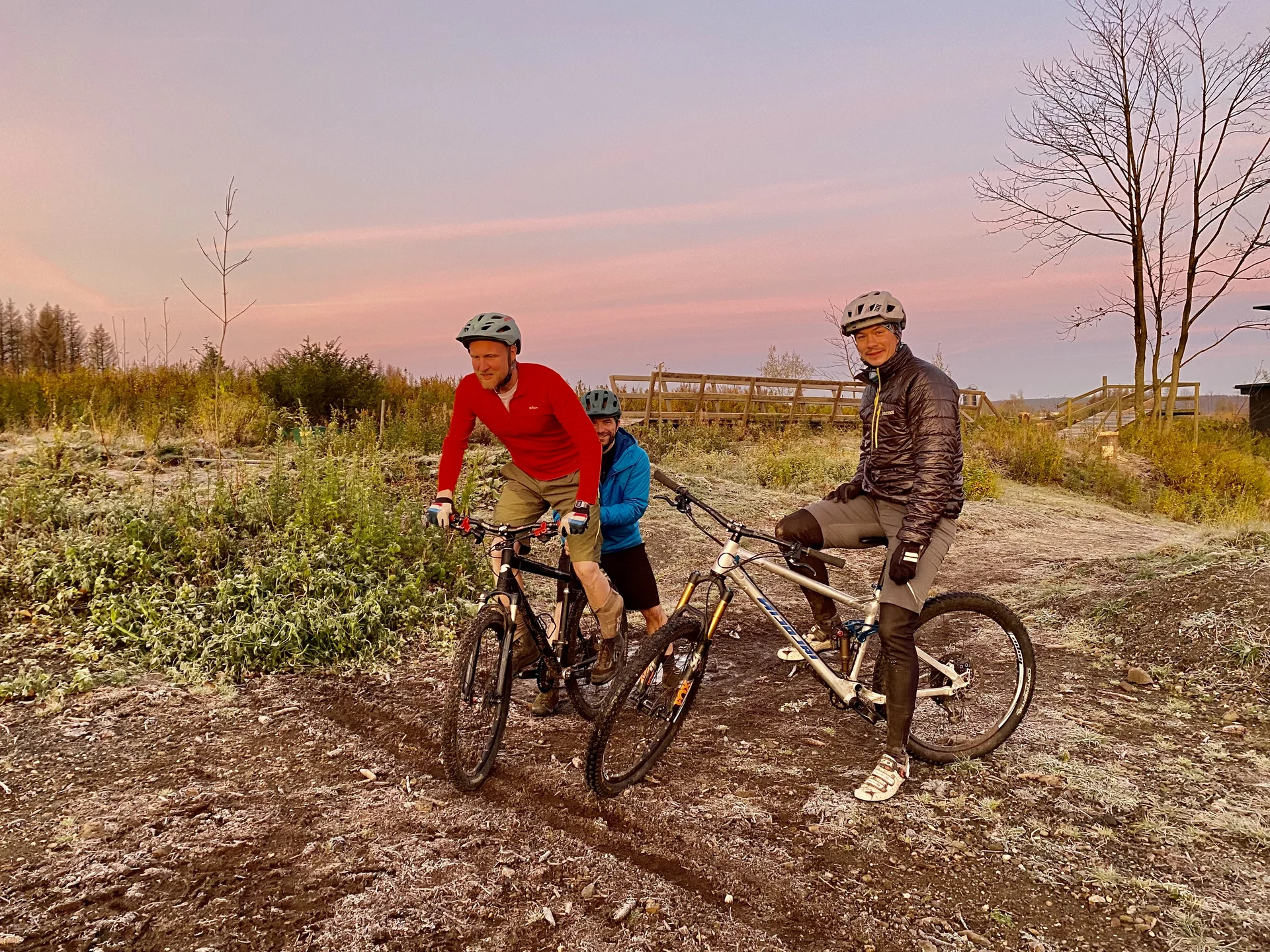 Drei Personen auf zwei Mountainbikes fahren bei frostigem Wetter durch eine flache Landschaft im Morgengrauen. | © DAV Dortmund