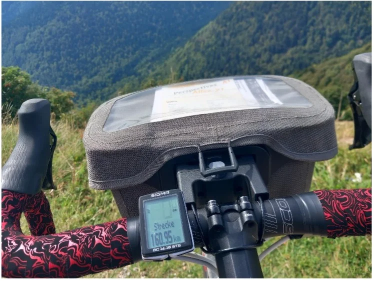 Blick über den Fahrradlenker mit Navigationsgerät und Roadbook in bergiger Umgebung. | © DAV Dortmund