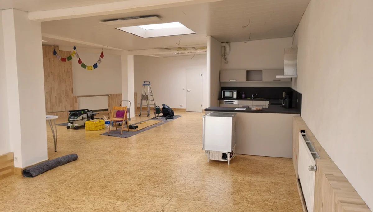 Blick in einen modernen, renovierten Raum mit Küche, Arbeitsmaterialien und Gebetsfahnen. | © DAV Dortmund