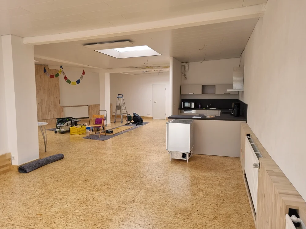Blick in einen modernen, renovierten Raum mit Küche, Arbeitsmaterialien und Gebetsfahnen. | © DAV Dortmund
