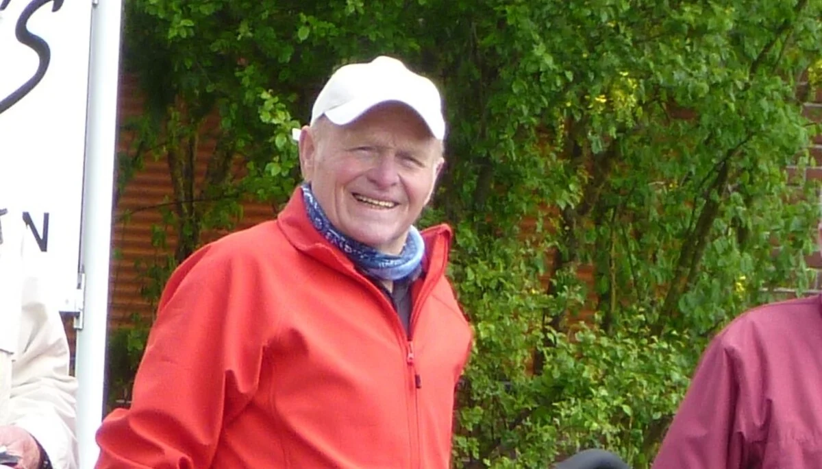 Ein Mann steht neben seinem Fahrrad und lächelt, im Hintergrund grüne Wiese und Bäume. | © DAV Dortmund