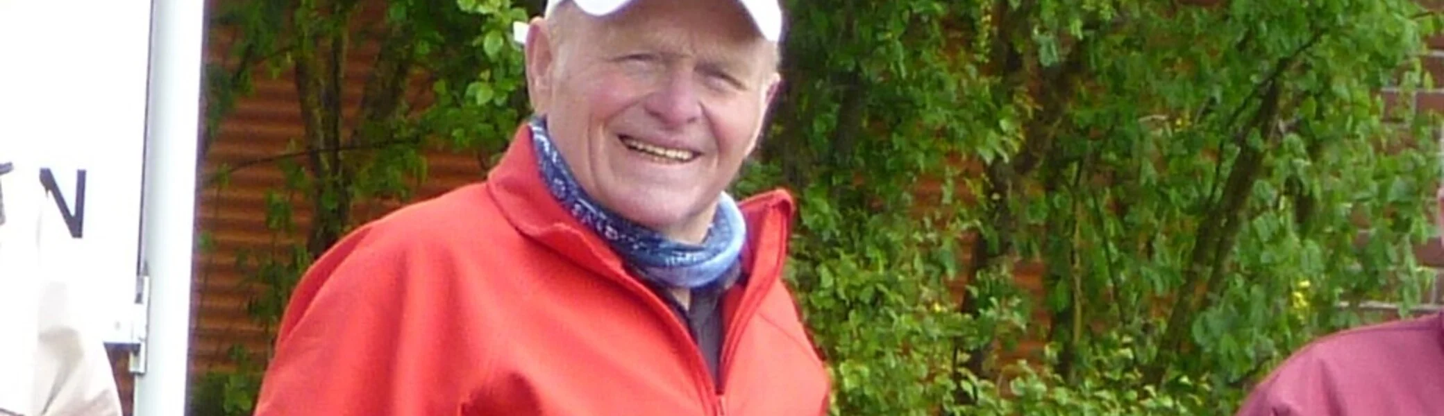 Ein Mann steht neben seinem Fahrrad und lächelt, im Hintergrund grüne Wiese und Bäume. | © DAV Dortmund