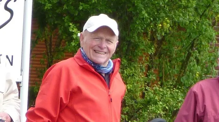 Ein Mann steht neben seinem Fahrrad und lächelt, im Hintergrund grüne Wiese und Bäume. | © DAV Dortmund