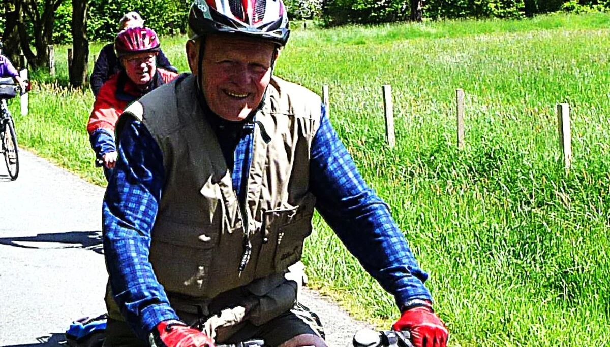 Ein älterer Mann mit Helm fährt bei Sonnenschein auf einem Fahrrad entlang einer Landstraße. | © DAV Dortmund