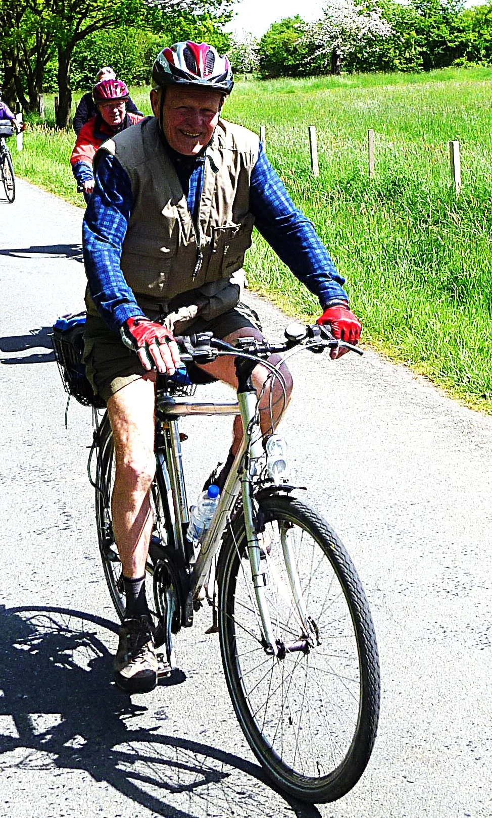 Ein älterer Mann mit Helm fährt bei Sonnenschein auf einem Fahrrad entlang einer Landstraße. | © DAV Dortmund