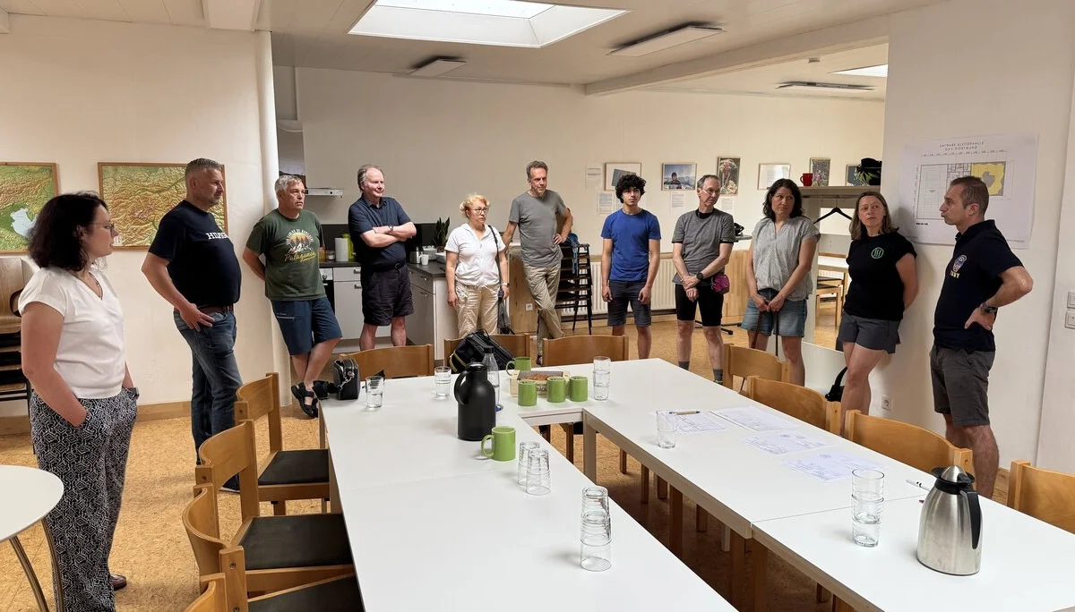 Eine Gruppe von Personen steht im Kreis um einen Tisch während einer Besprechung. | © DAV Dortmund