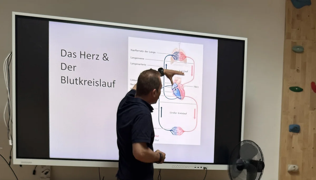 Ein Mann zeigt auf eine Folie mit einer medizinischen Darstellung des Blutkreislaufs während einer Präsentation. | © DAV Dortmund