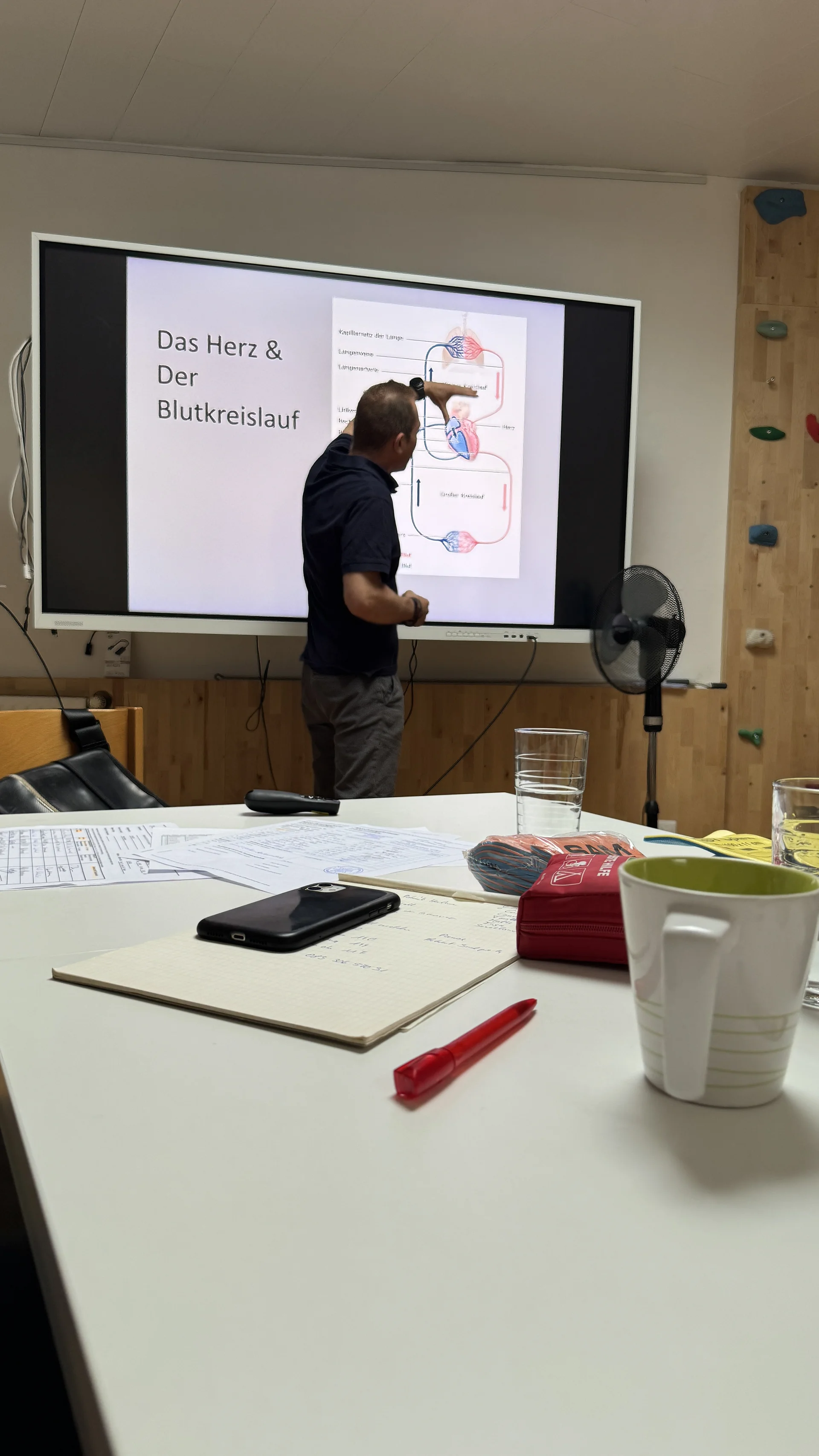 Ein Mann zeigt auf eine Folie mit einer medizinischen Darstellung des Blutkreislaufs während einer Präsentation. | © DAV Dortmund