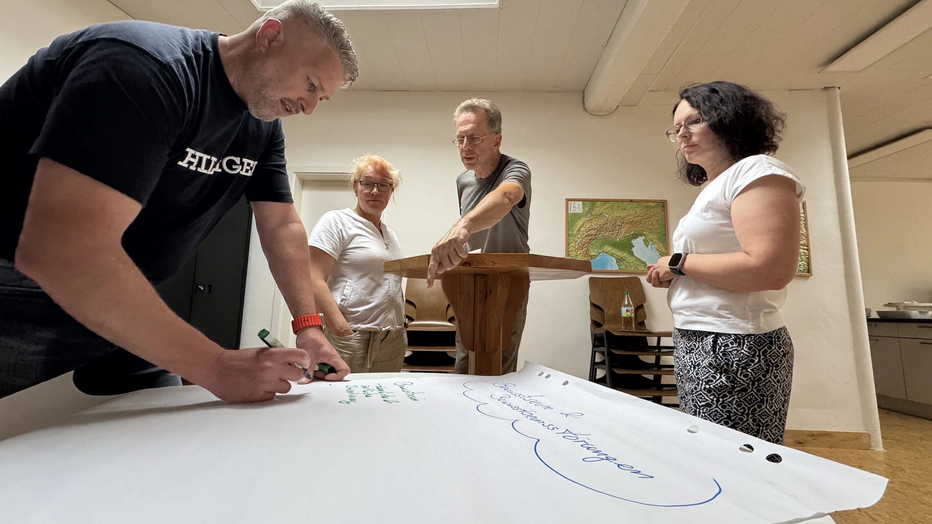 Zwei Frauen und zwei Männer schreiben Ideen auf ein großes Papier, ein Mann steht am Pult. | © DAV Dortmund