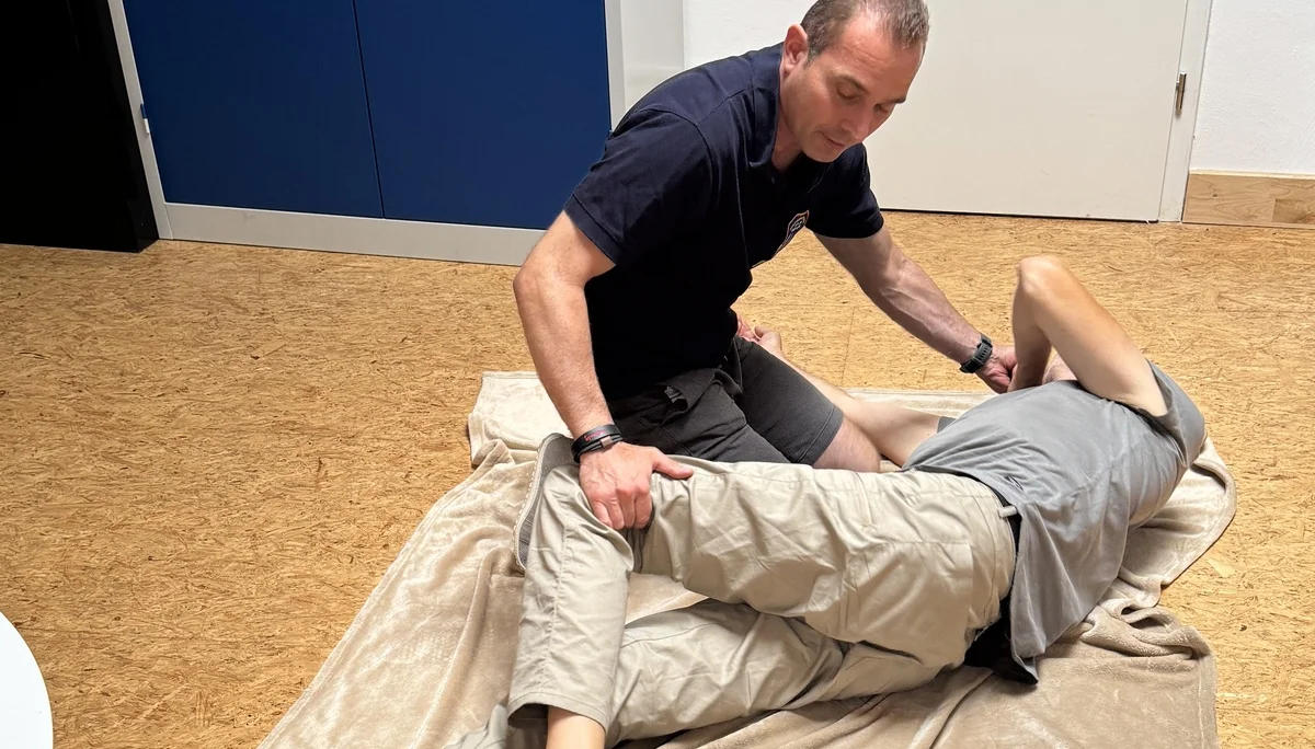 Person übt stabile Seitenlage mit einem Übungspartner auf einer Decke. | © DAV Dortmund