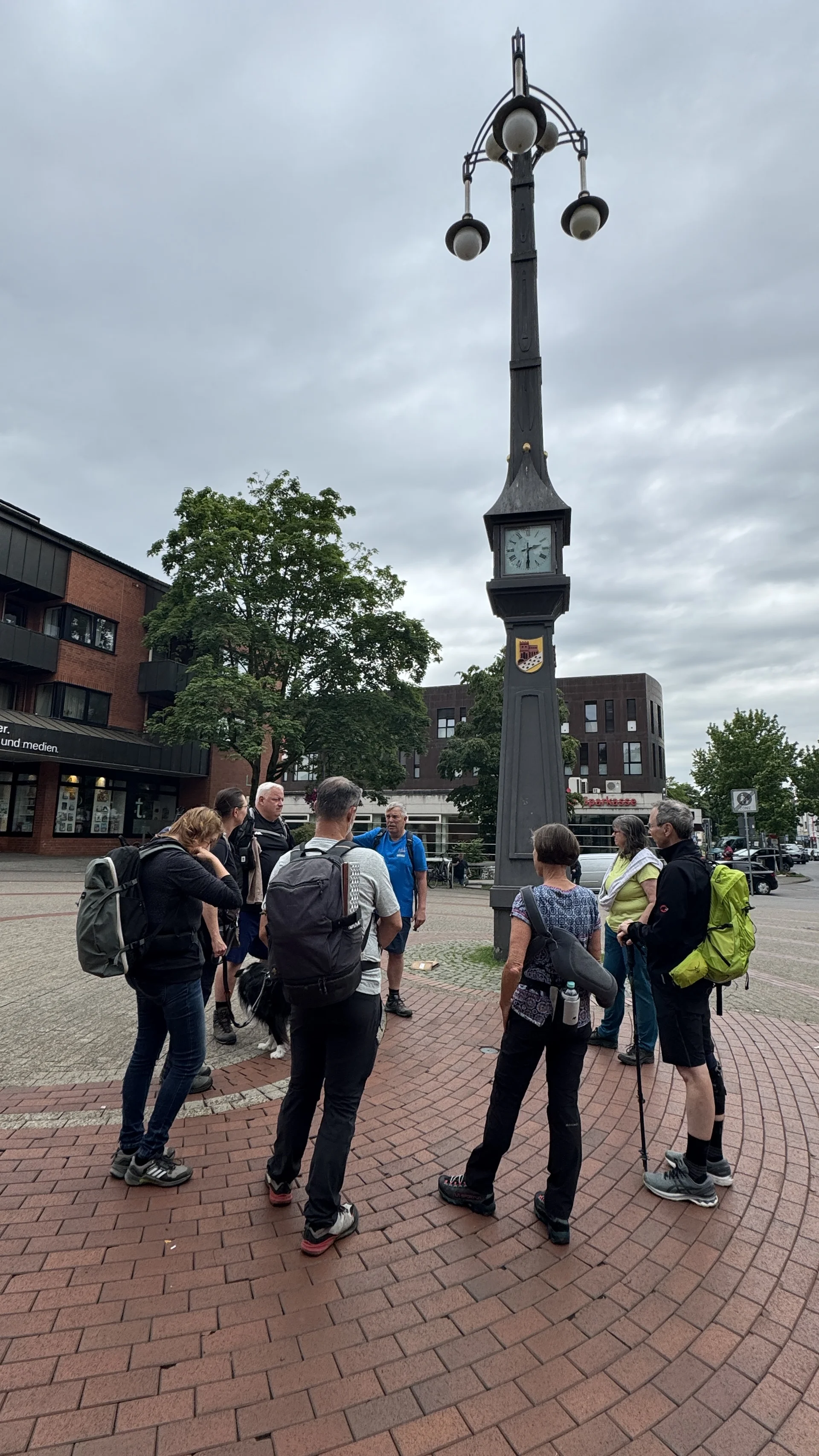 Eine Wandergruppe steht vor einer großen schwarzen Uhrsäule auf einem Platz. | © DAV Dortmund