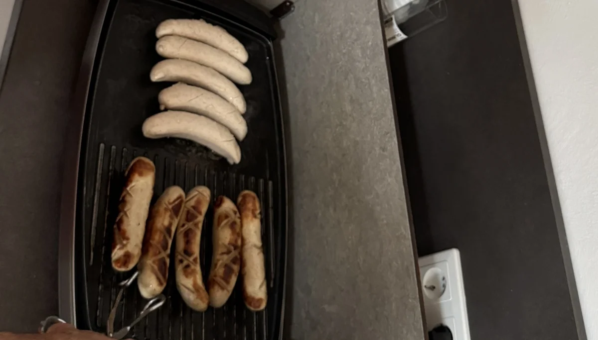 Ein Mann brät mehrere Würste in einer elektrischen Pfanne. | © DAV Dortmund