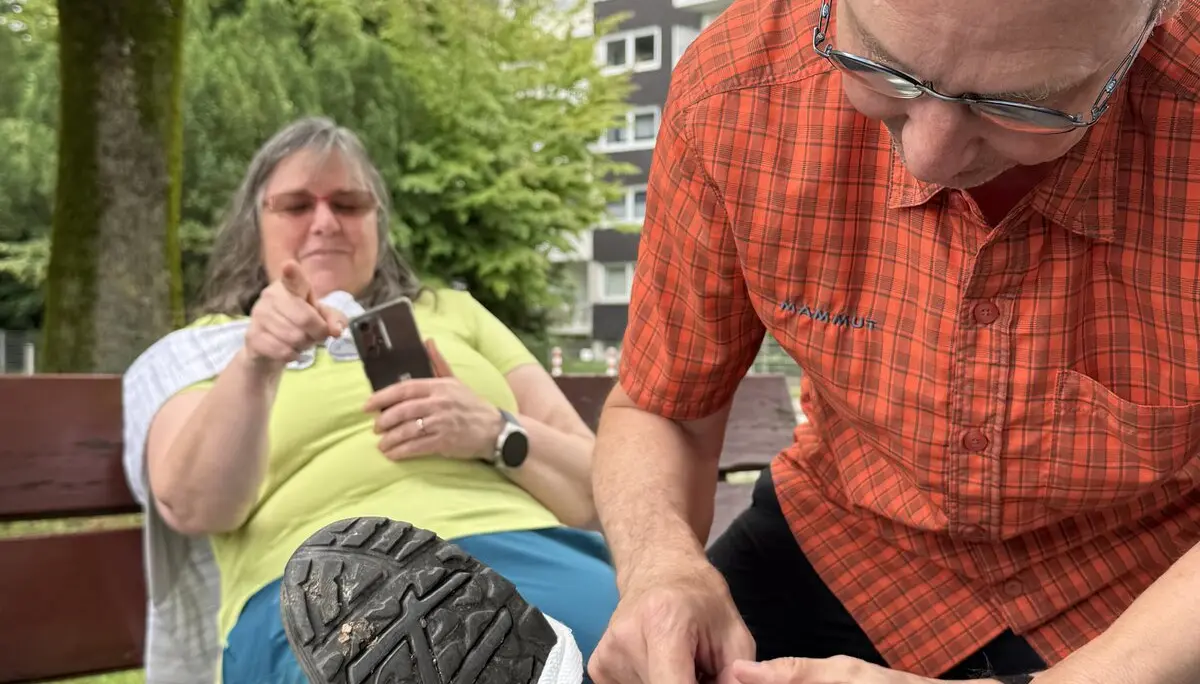 Ein Mann versorgt einen Fuß mit Verbandmaterial, eine Frau sitzt im Hintergrund auf der Bank. | © DAV Dortmund