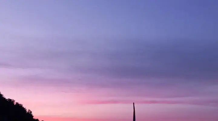 Ein Bergpanorama bei Sonnenuntergang mit violettem Himmel und markanter Säule im Vordergrund. | © DAV Dortmund