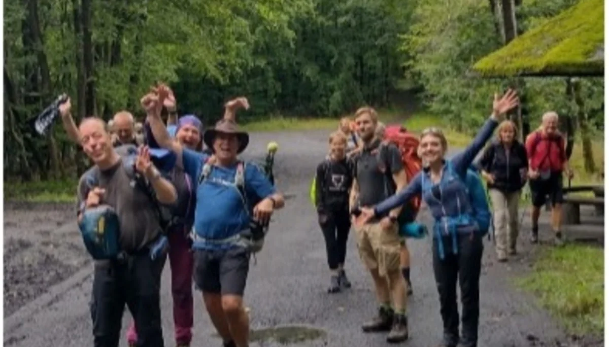 Gruppe von Wandernden posiert lachend auf einer Waldstraße | © DAV Dortmund