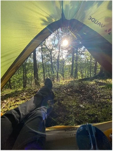 Blick aus einem geöffneten Zelt auf einen sonnigen Wald am Morgen. | © DAV Dortmund