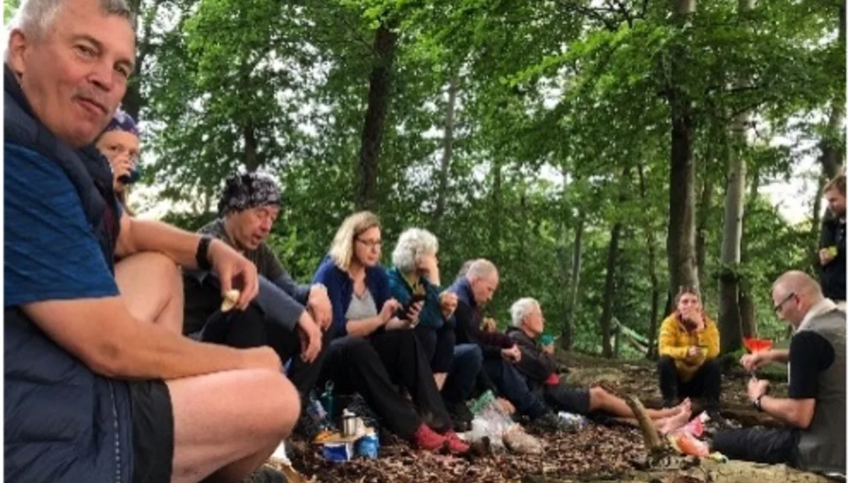 Gruppe von Wandernden macht eine Pause im Wald und sitzt auf dem Waldboden. | © DAV Dortmund