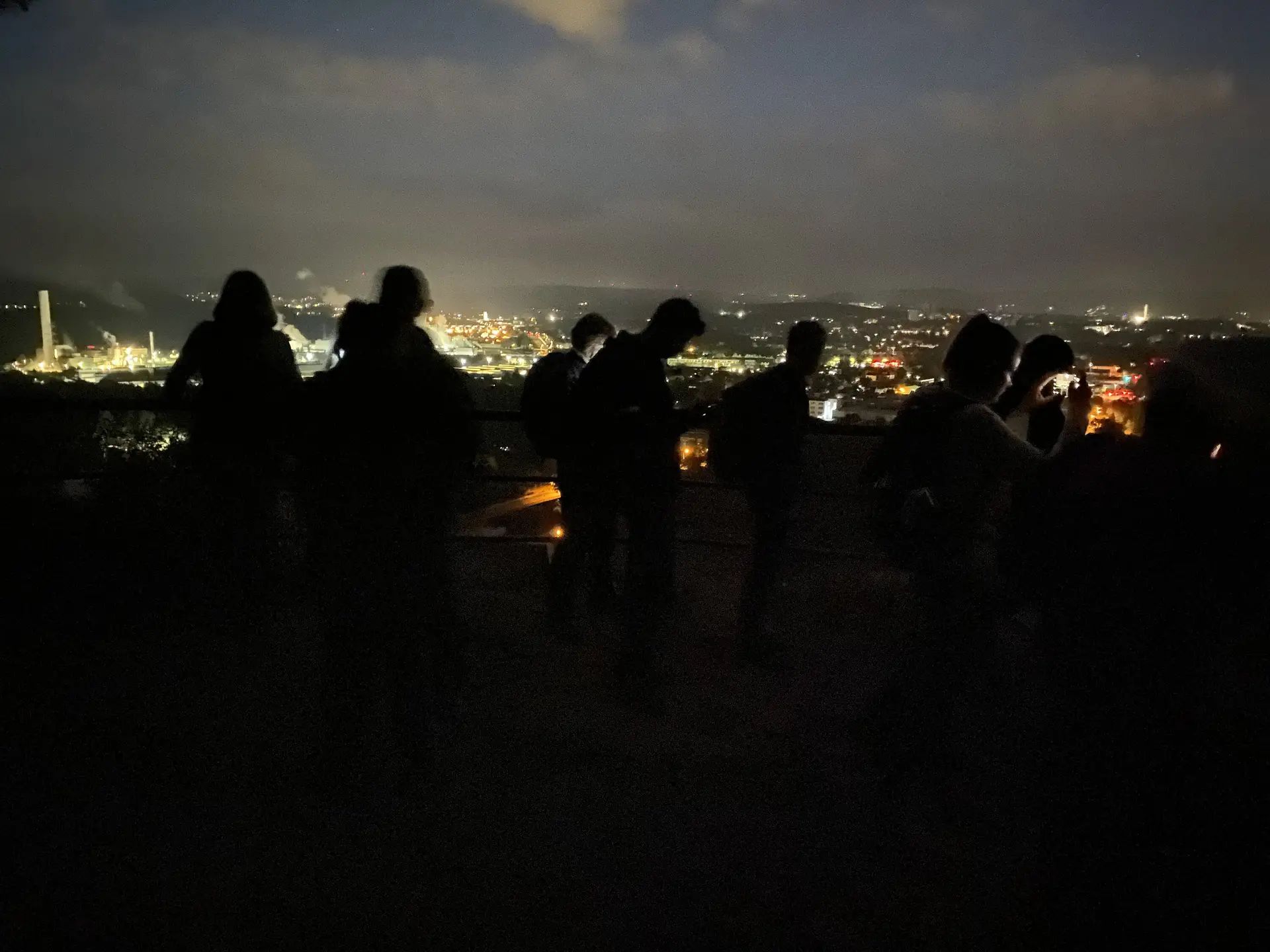 Silhouetten mehrerer Personen bei Nacht mit Blick auf eine beleuchtete Stadtlandschaft. | © DAV Dortmund