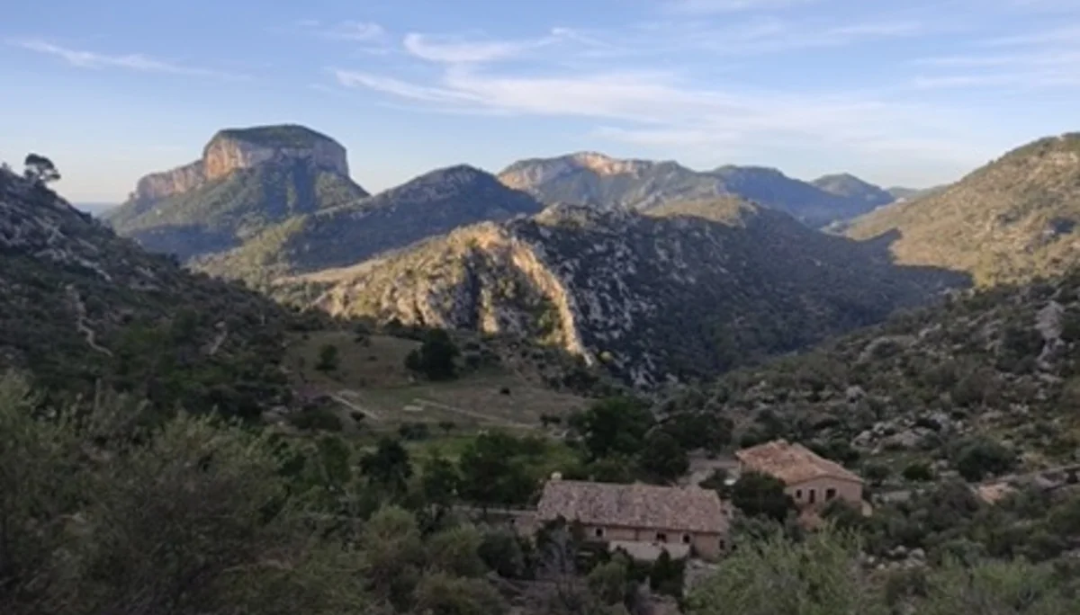 Blick auf ein weites Tal mit Bergen und einer alten Steinhütte im Vordergrund. | © DAV Dortmund