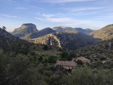 Blick auf ein weites Tal mit Bergen und einer alten Steinhütte im Vordergrund. | © DAV Dortmund